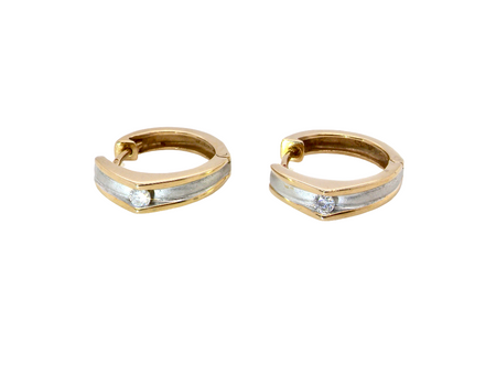 A pair of gold huggie hoop earrings with a textured silver-colored center channel and a small clear gemstone on each earring, shown against a plain white background.