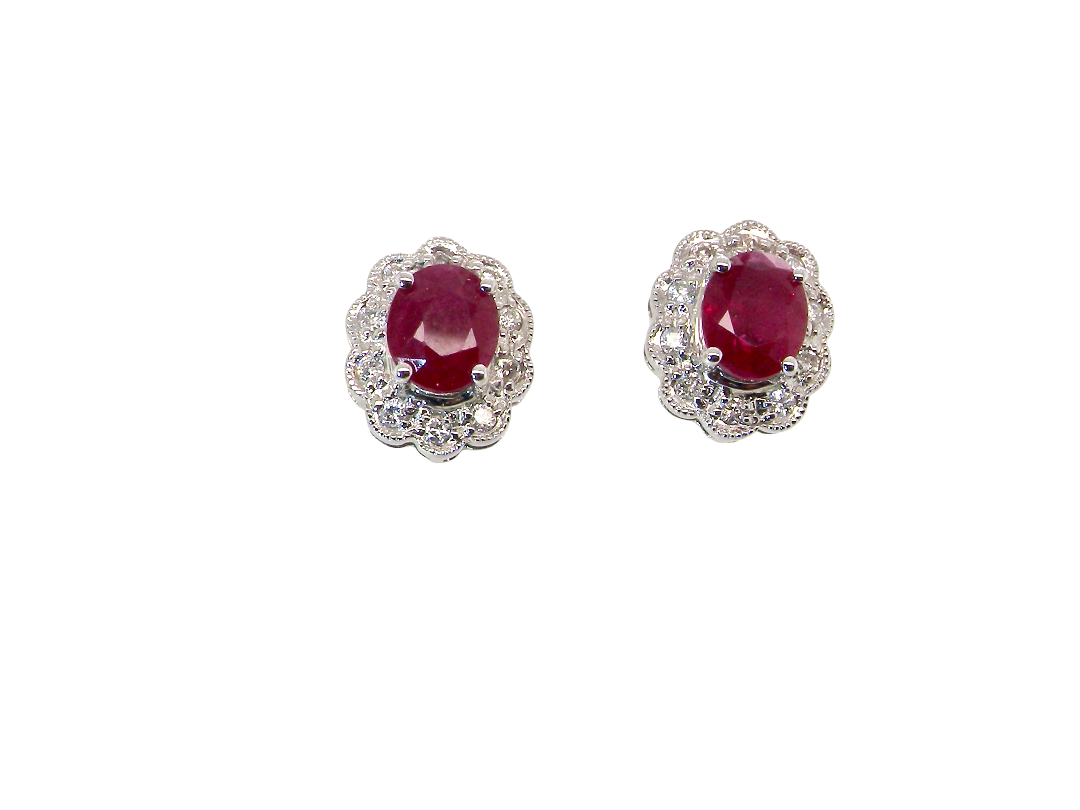 A pair of white gold earrings, each set with an oval ruby 6x4.9mm (est 0.60 carats) complimented by an outer halo of ten 1.5mm diamonds