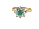 A yellow gold ring featuring a central round green emerald-cut gemstone surrounded by a halo of small clear round-cut stones, set on a plain white background.