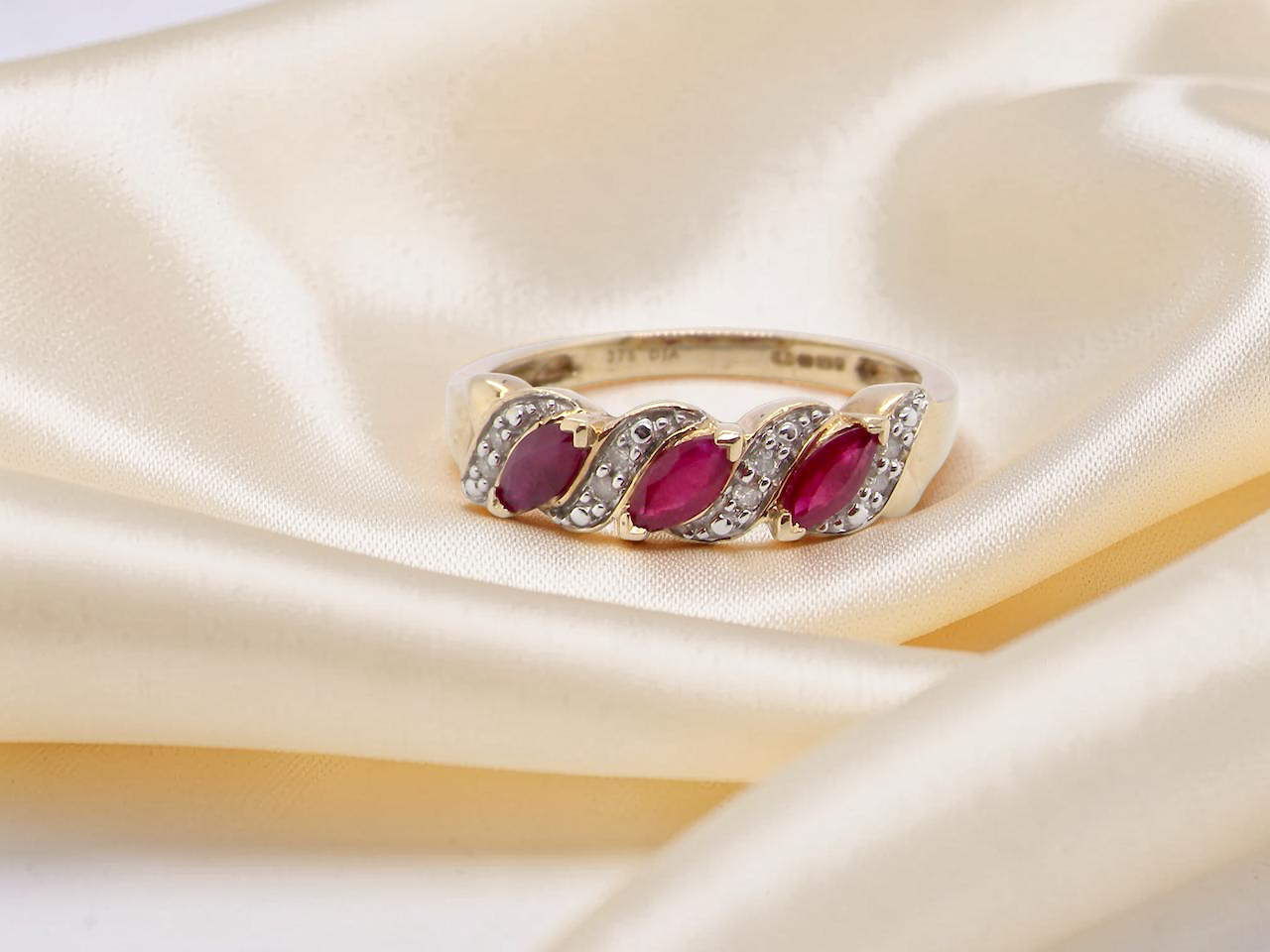 A pretty 9 carat gold dress ring. The three rubies are marquise cut,  and set at an angle .