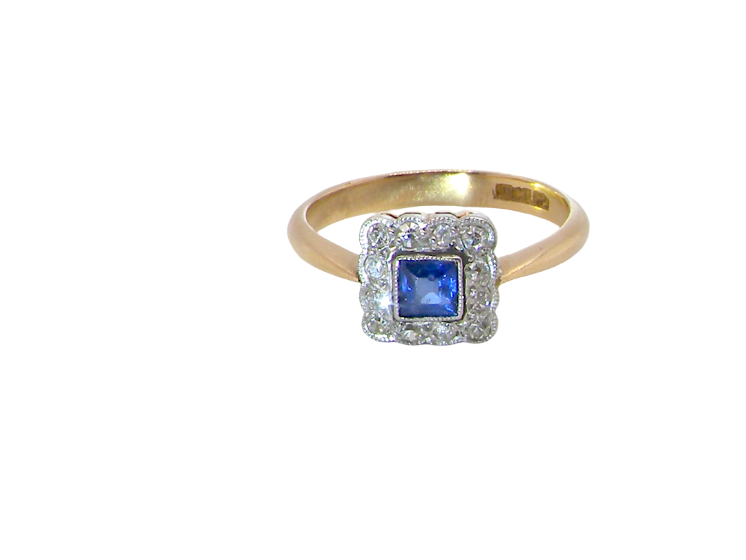 A pretty square cluster ring. Features to the centre a cornflower blue square sapphire, 4x4mm (est 0.30 carats) mille grain set.

Complimented by a halo of twelve x 1.5 mm  white diamonds 