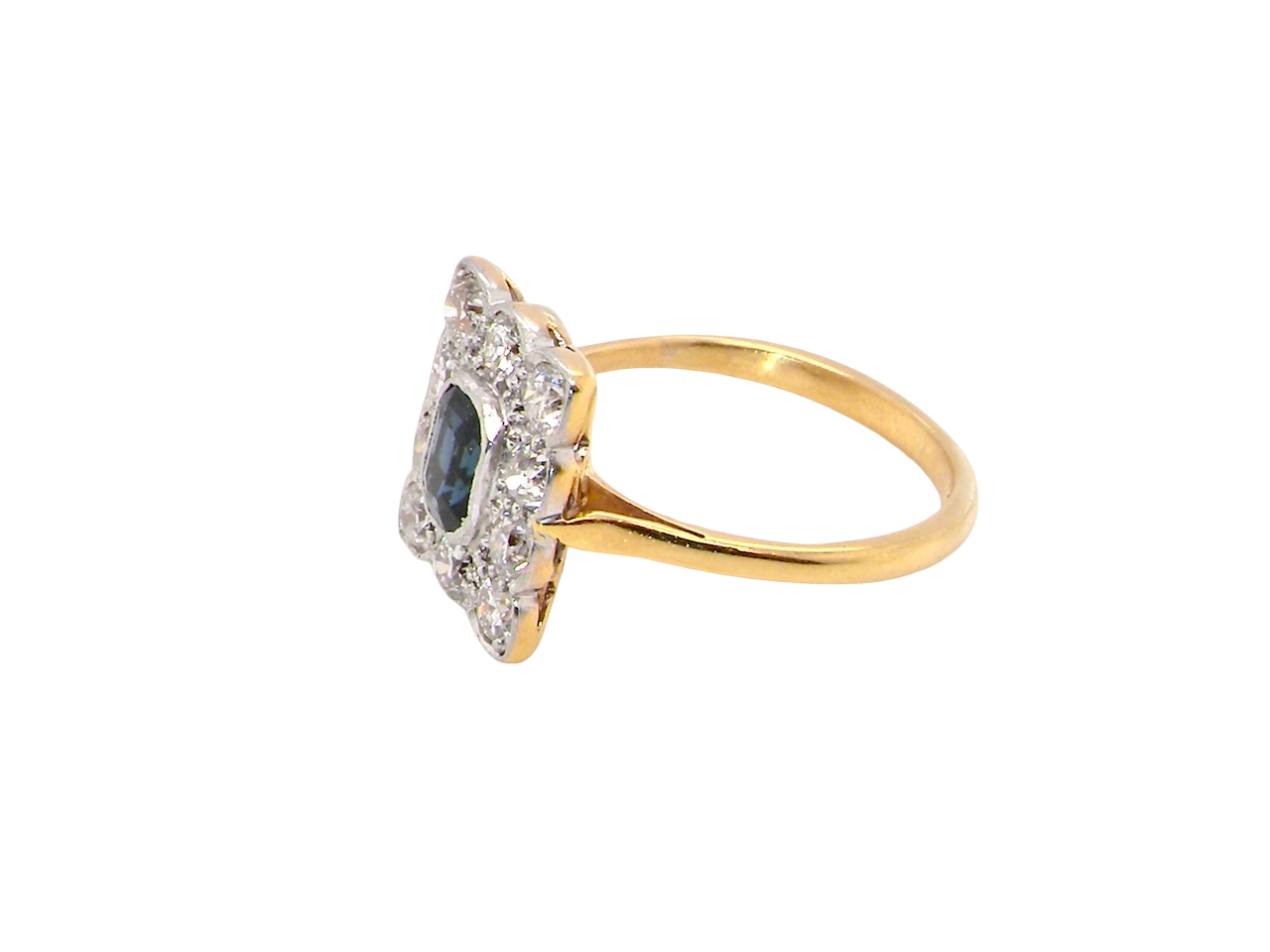 A rectangular cluster ring that features in its centre a cushion shaped dark blue sapphire, that measures 5x3.5mm (est 0.30 carats) side