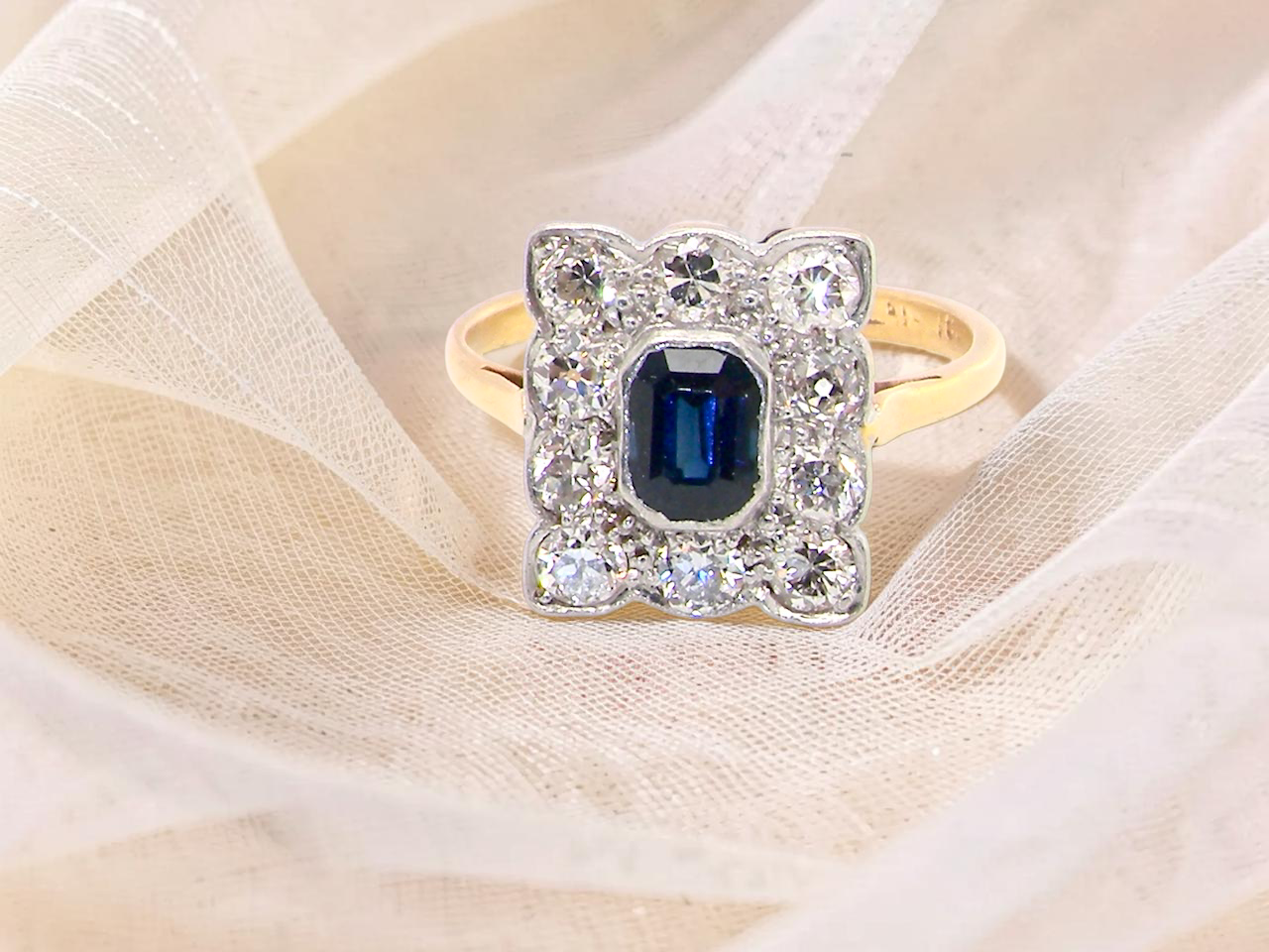 A rectangular cluster ring that features in its centre a cushion shaped dark blue sapphire, that measures  (est 0.30 carats)