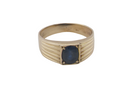 A solitaire dress ring that features an oval cut dark blue sapphire, 6x5mm. Wide ribbed patterned shoulders, 7mm width and tapering to a 3.8mm shank at the reverse.