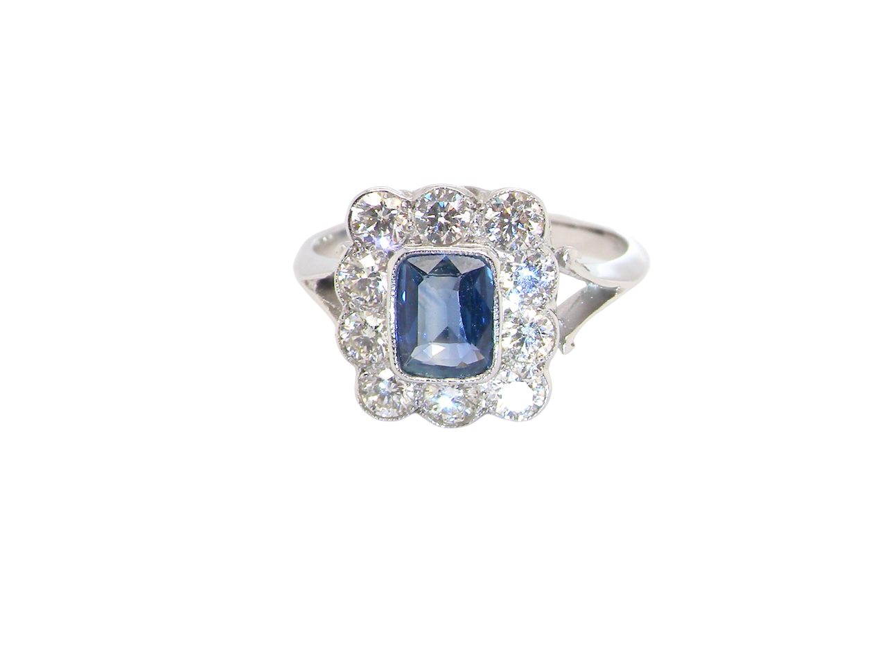 A stunning Art Deco cluster ring featuring a rich mid- to dark ink-blue sapphire,