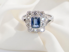 A stunning Art Deco cluster ring featuring a rich mid- to dark ink-blue sapphire