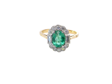 A stunning vintage cluster ring, set with an oval-cut emerald measuring 8 x 6mm, approximately 1.10 carats. The emerald displays a rich, deep grass-green colour with natural inclusions, typical of a genuine stone.