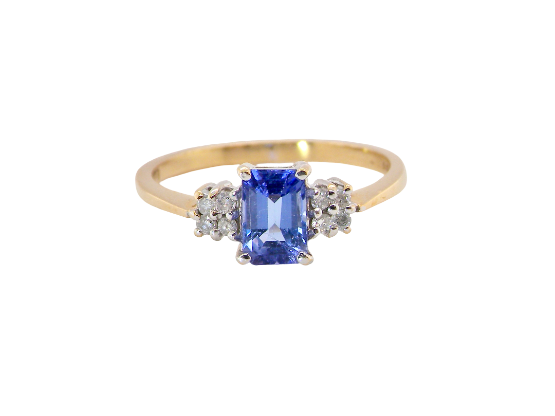 A three stone 18 carat gold ring. Features a rectangular tanzanite centre stone 6x4mm (