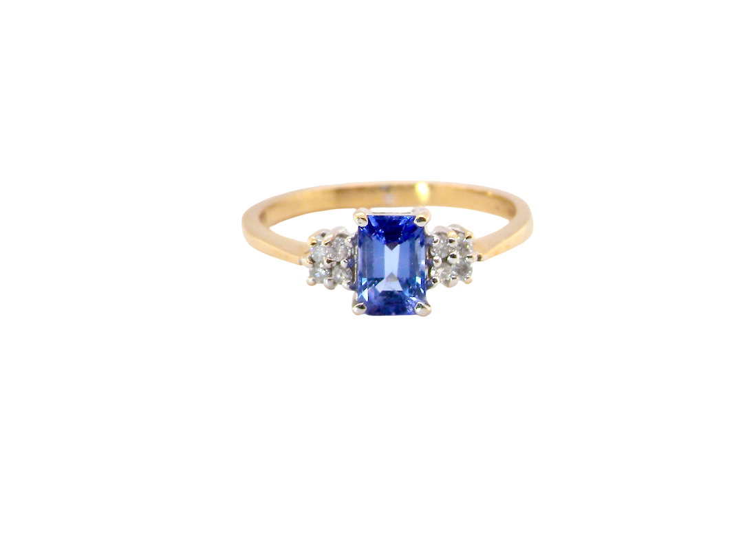 A three stone 18 carat gold ring. Features a rectangular tanzanite centre stone 6x4mm (est 0.50 carats)