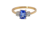 A three stone 18 carat gold ring. Features a rectangular tanzanite centre stone (est 0.50 carats)