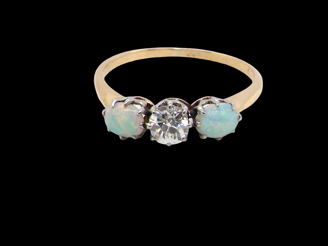 A three stone ring, the centre stone an old brilliant cut white diamond 4.6mm (est 0.38 carats) opal