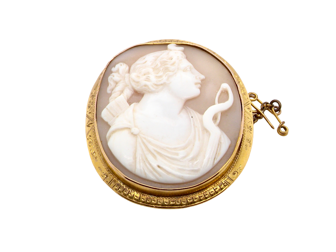 An antique-style oval cameo brooch featuring a carved white classical female profile on a warm beige background, set in a gold-toned bezel with a small gold clasp, shown on a plain white background.