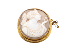 An antique-style oval cameo brooch featuring a carved white classical female profile on a warm beige background, set in a gold-toned bezel with a small gold clasp, shown on a plain white background.
