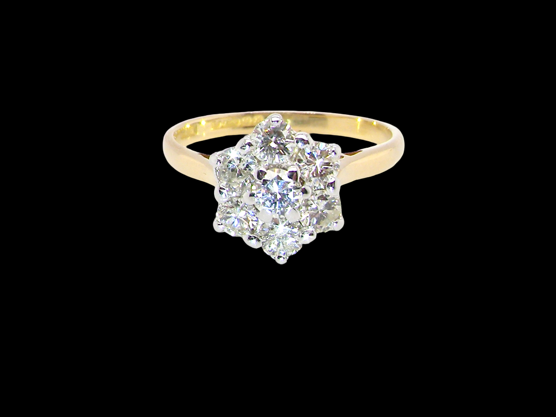 A traditional cluster ring. Features to the centre a 3.4mm brilliant cut white diamond (est 0.15 carats)

Surrounded by  3.4mm diamonds to match