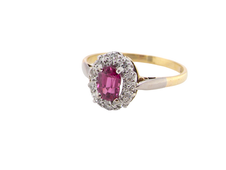 A traditional cluster ring. Features to the centre a dark pink red ruby, oval cut 6x4mm 