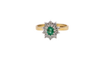 A traditional cluster ring. Features to the centre an oval shaped emerald, 5.5x4.5mm (est 0.35 carats) deep green colour.&nbsp;