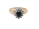 A traditional cluster ring that features to the centre a dark black blue oval cut sapphire 7x5mm  claw set.