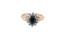 A traditional cluster ring that features to the centre a dark black blue oval cut sapphire 7x5mm (est 3/4 ct) claw set.