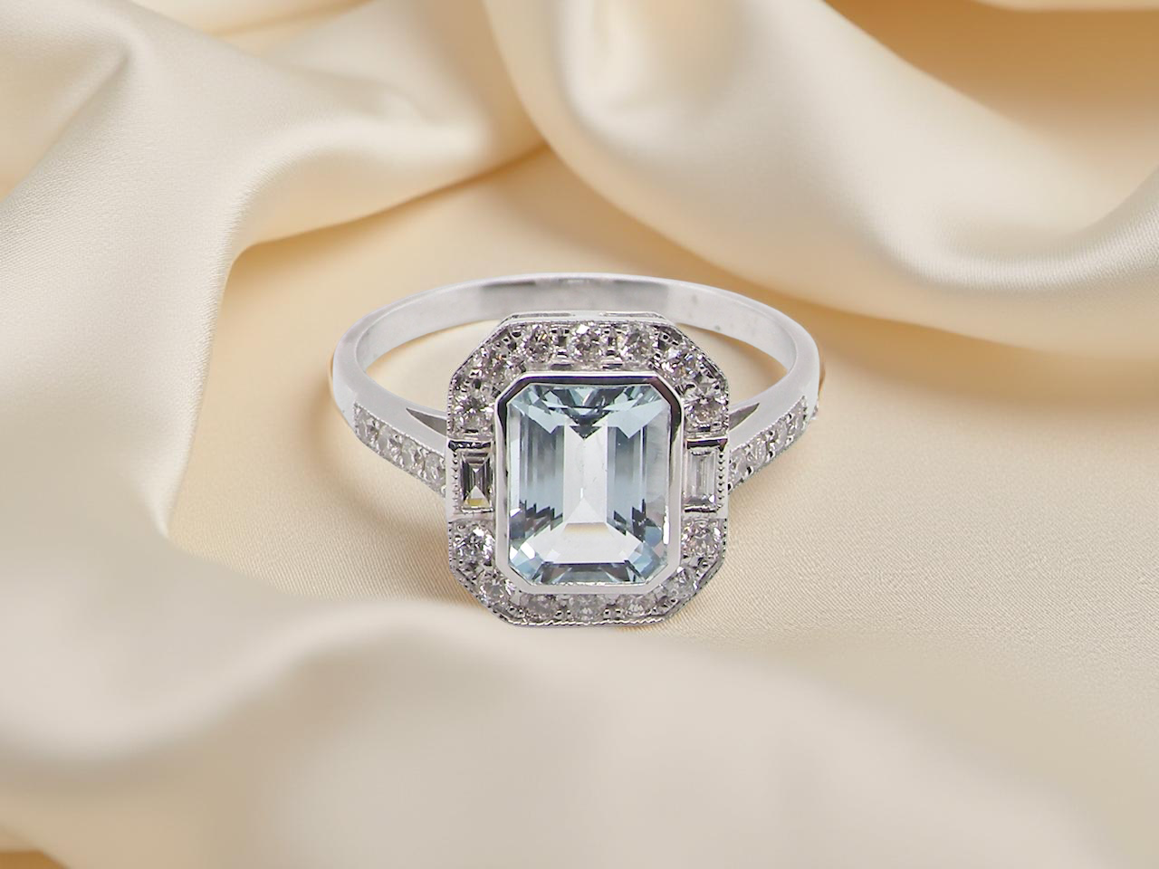 A very pretty cluster ring. Features a step cut aquamarine centre stone, 8x7mm (est 1.21 carats). Plain rim setting. A