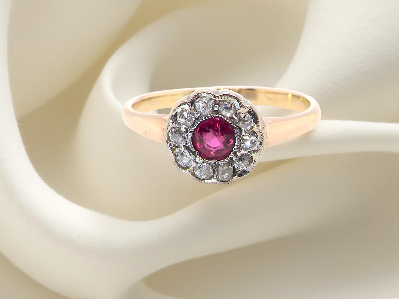 A very pretty vintage daisy cluster ring. Features to the centre a round pink red ruby that measures 4mm, 