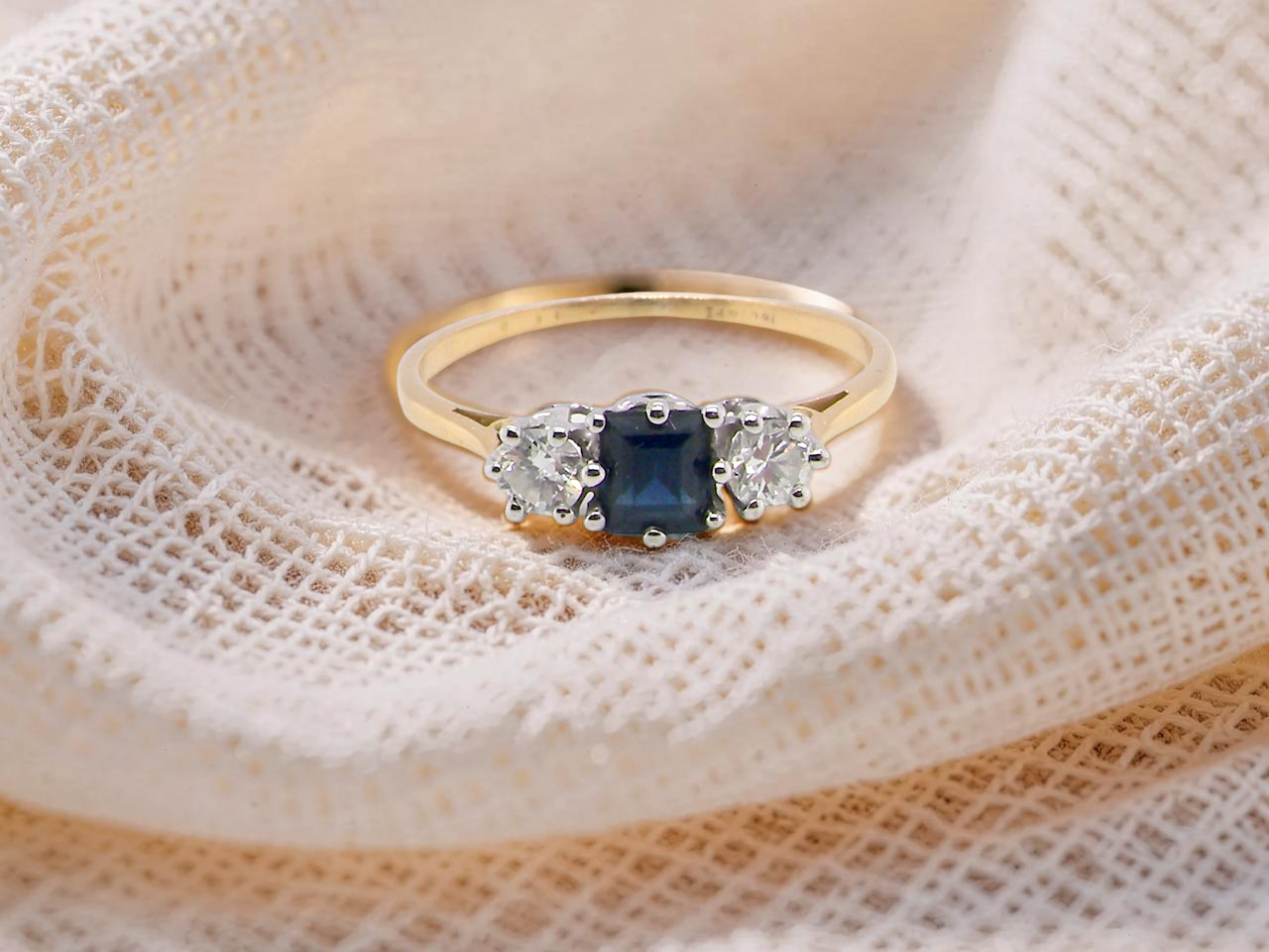 A vintage 1950s three stone ring. Centre stone an ink black blue sapphire, measures 4x4mm (est 0.30 carats).

