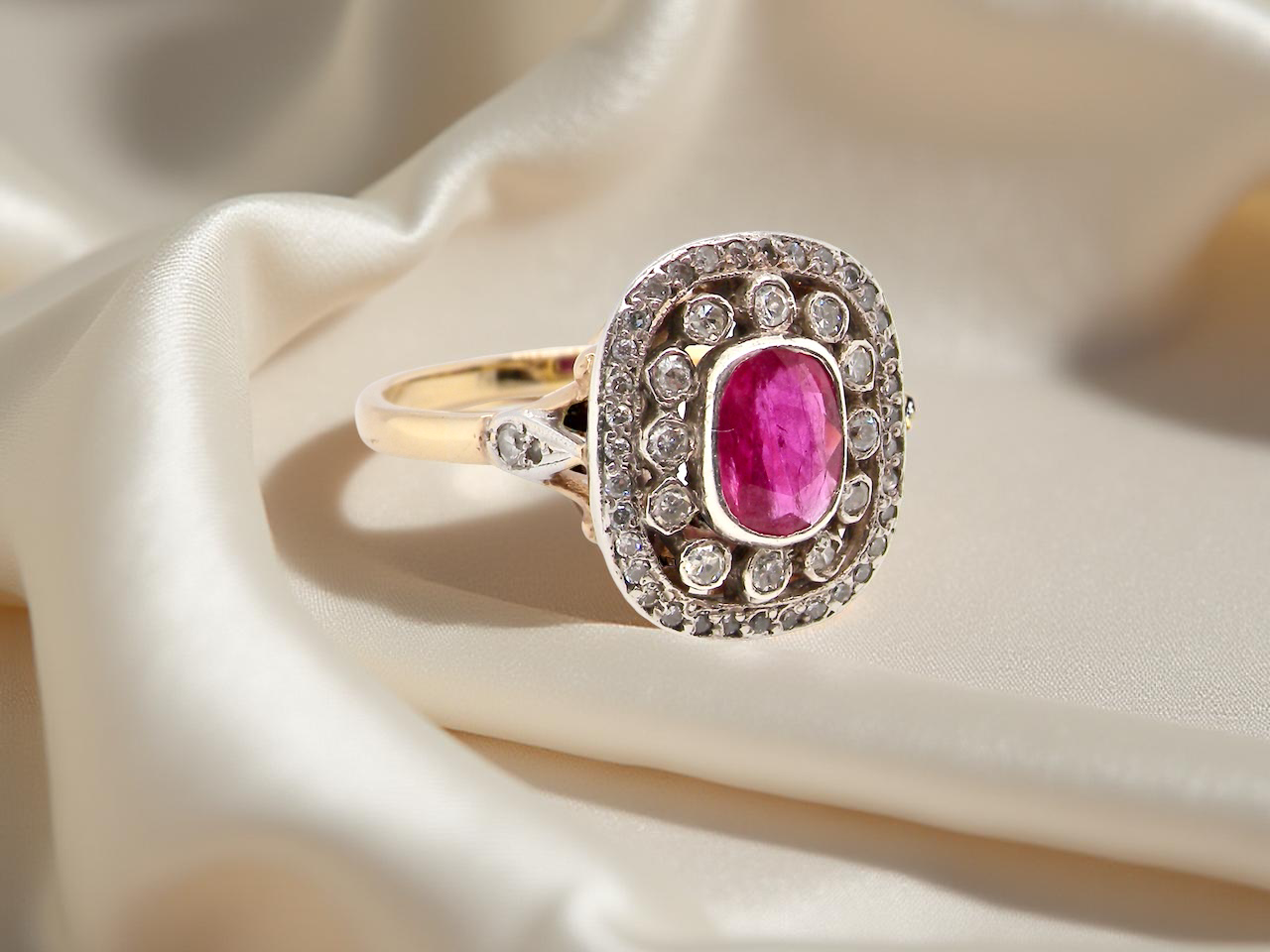 Gold ring with a pink gemstone and diamond accents on beige fabric