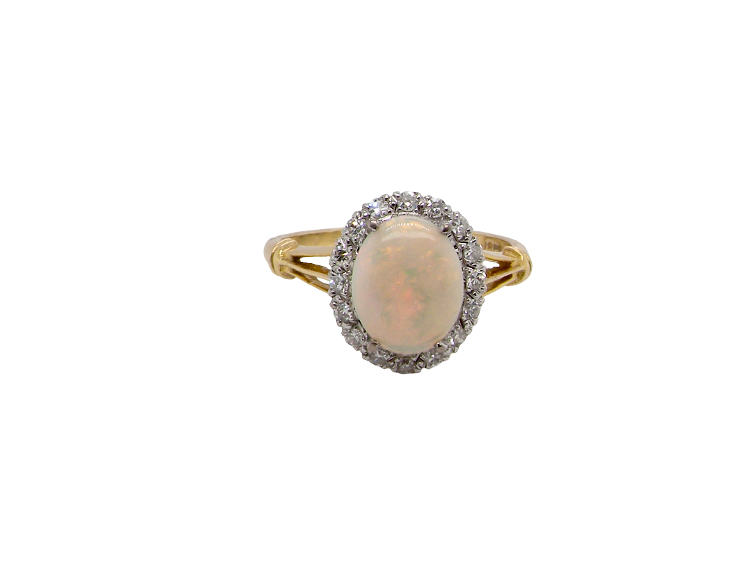 A vintage cluster ring. Features an oval white opal, measures 10x8mm, with a good play of colour.