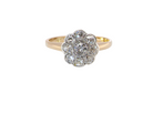 A vintage-style cluster ring featuring a central cluster of round diamonds in a silver-toned setting, mounted on a yellow gold band, shown against a plain white background.