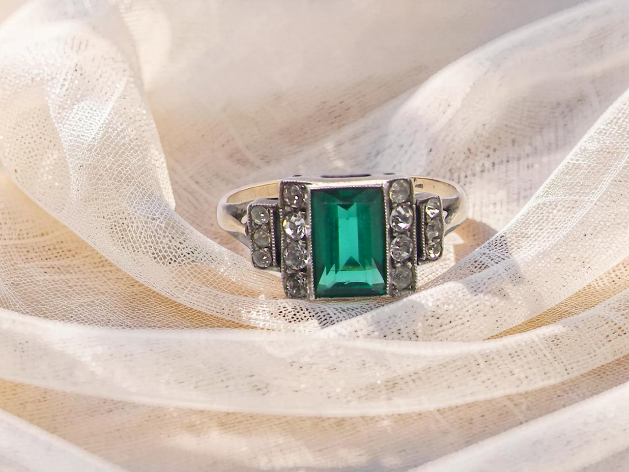 A vintage early 20th century dress ring. The centre stone a vibrant crystal clear green stone, 8x6mm.