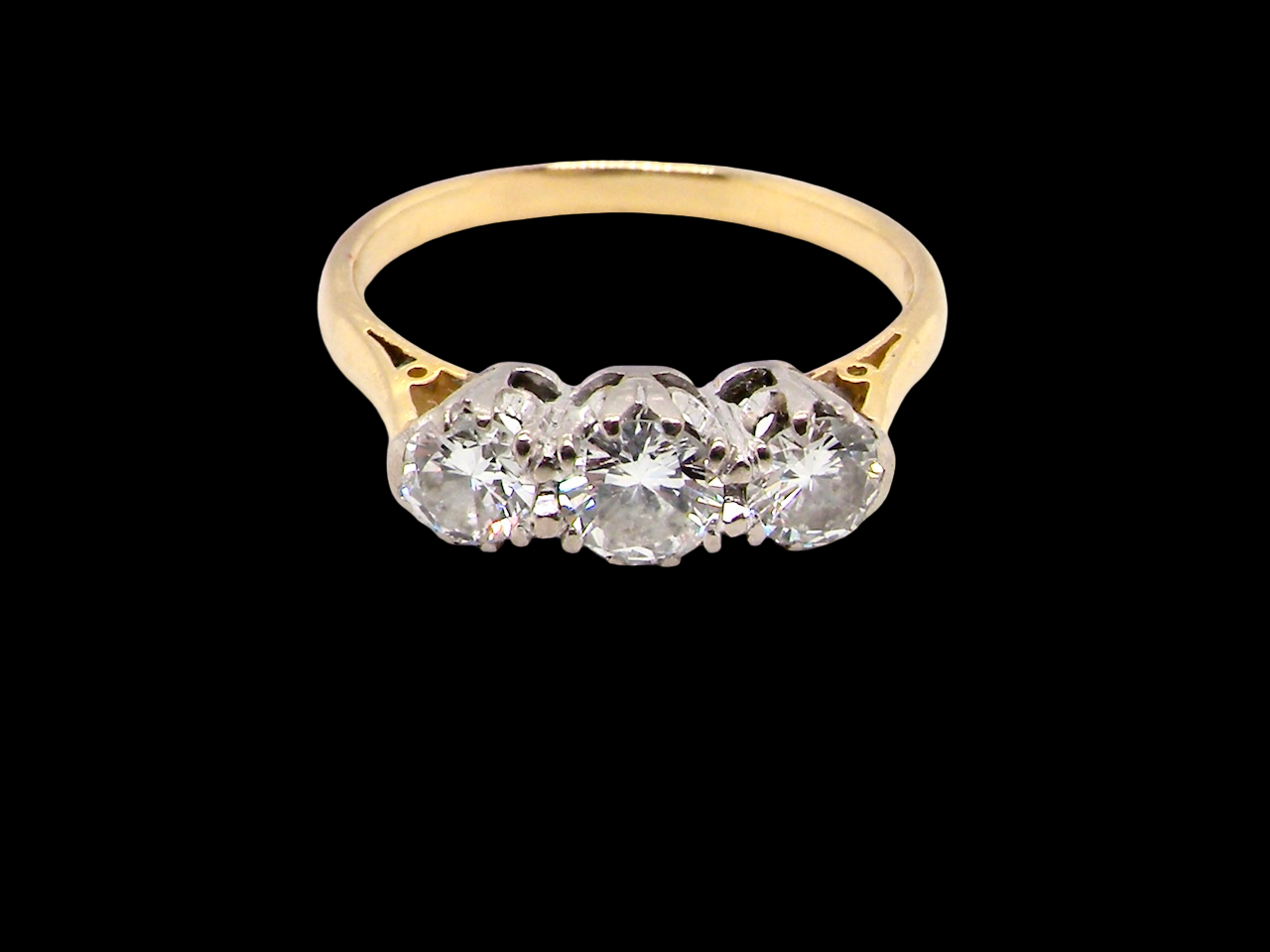 Gold ring with three diamonds on a black background