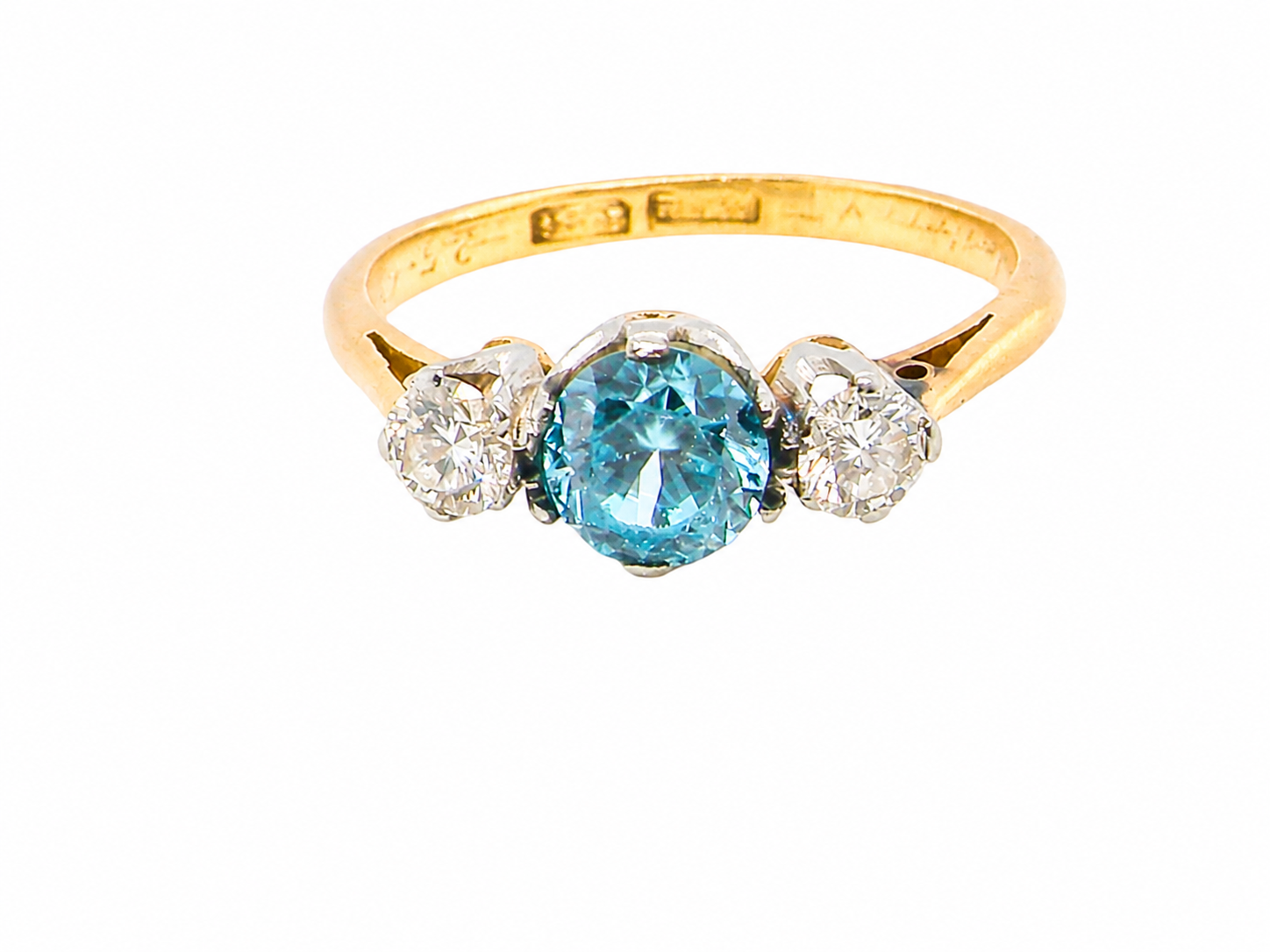 A vintage three stone ring. Centre stone, a round 5.8mm natural blue zircon.

To each side an old brilliant cut white diamond 4mm round (est 0.25 carats). 