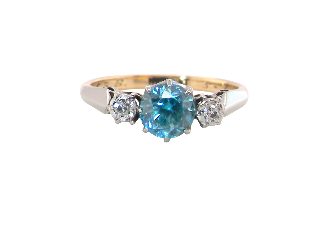 A vintage three stone ring. Features to the centre a 6mm natural blue zircon, 6mm diameter, 