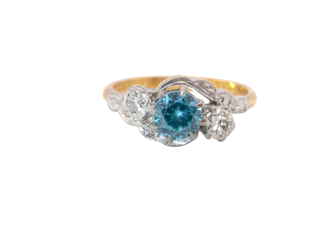 A vintage three stone ring, cross over style and features a round 6mm&nbsp; blue zircon centre stone