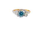 A vintage three stone ring, cross over style and features a round 6mm&nbsp; blue zircon centre stone