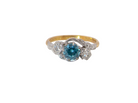 A vintage three stone ring, cross over style and features a round 6mm&nbsp; natural blue zircon centre stone
