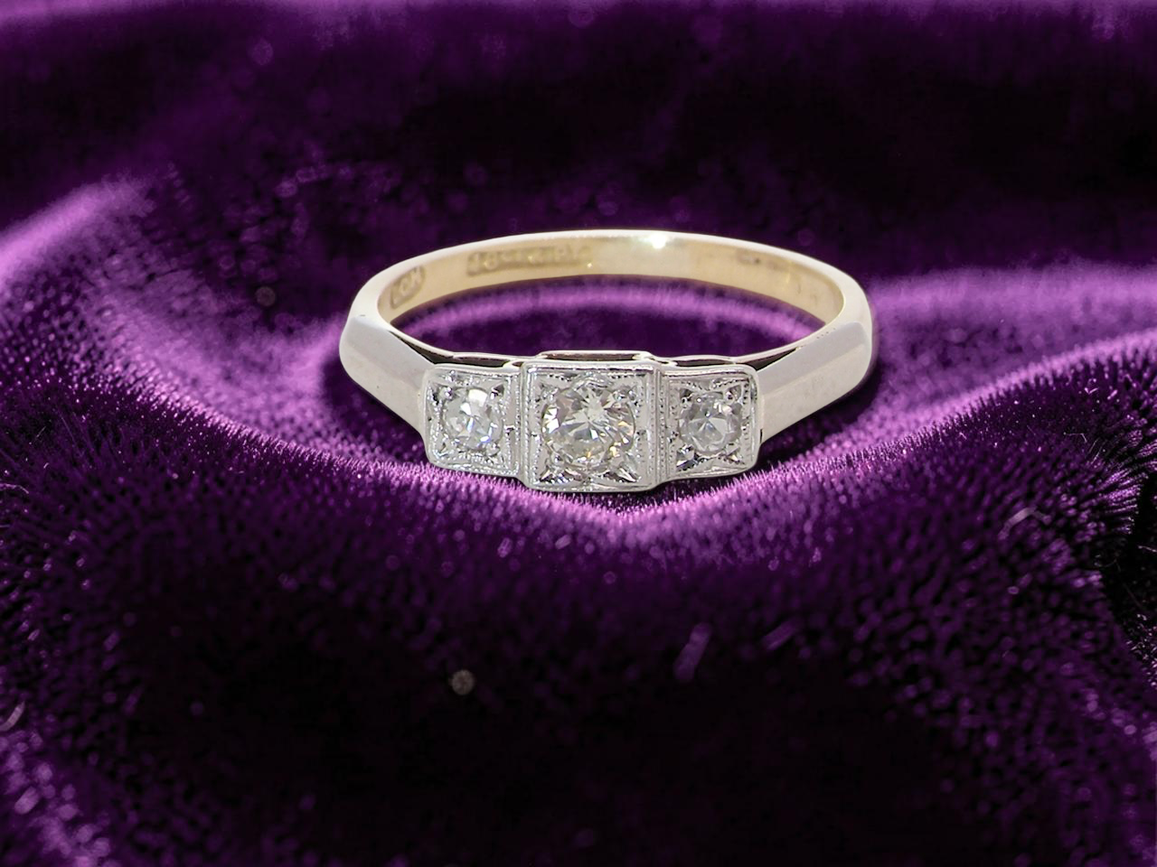A vintage trilogy ring. Set with three old brilliant cut white diamonds, centre 3mm and each side a 2.4mm diamond. Total estimated at 0.20 carats, 