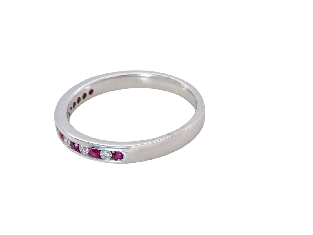 A white gold half hoop eternity ring. Set with seven round rubies and six brilliant cut white diamonds side