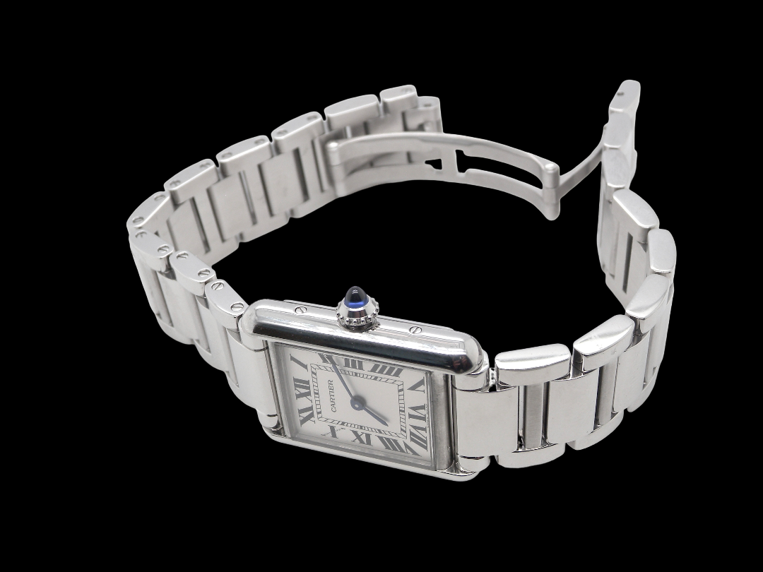 A womans stainless steel Cartier Tank Must wrist watch. Model number WSTA0051.

Silver coloured dial with Roman Numerals. Blue steeled hands. Case measures 29.5x22mm, case thickness 6.6mm. Quartz movement, synthetic sapphire button.
side