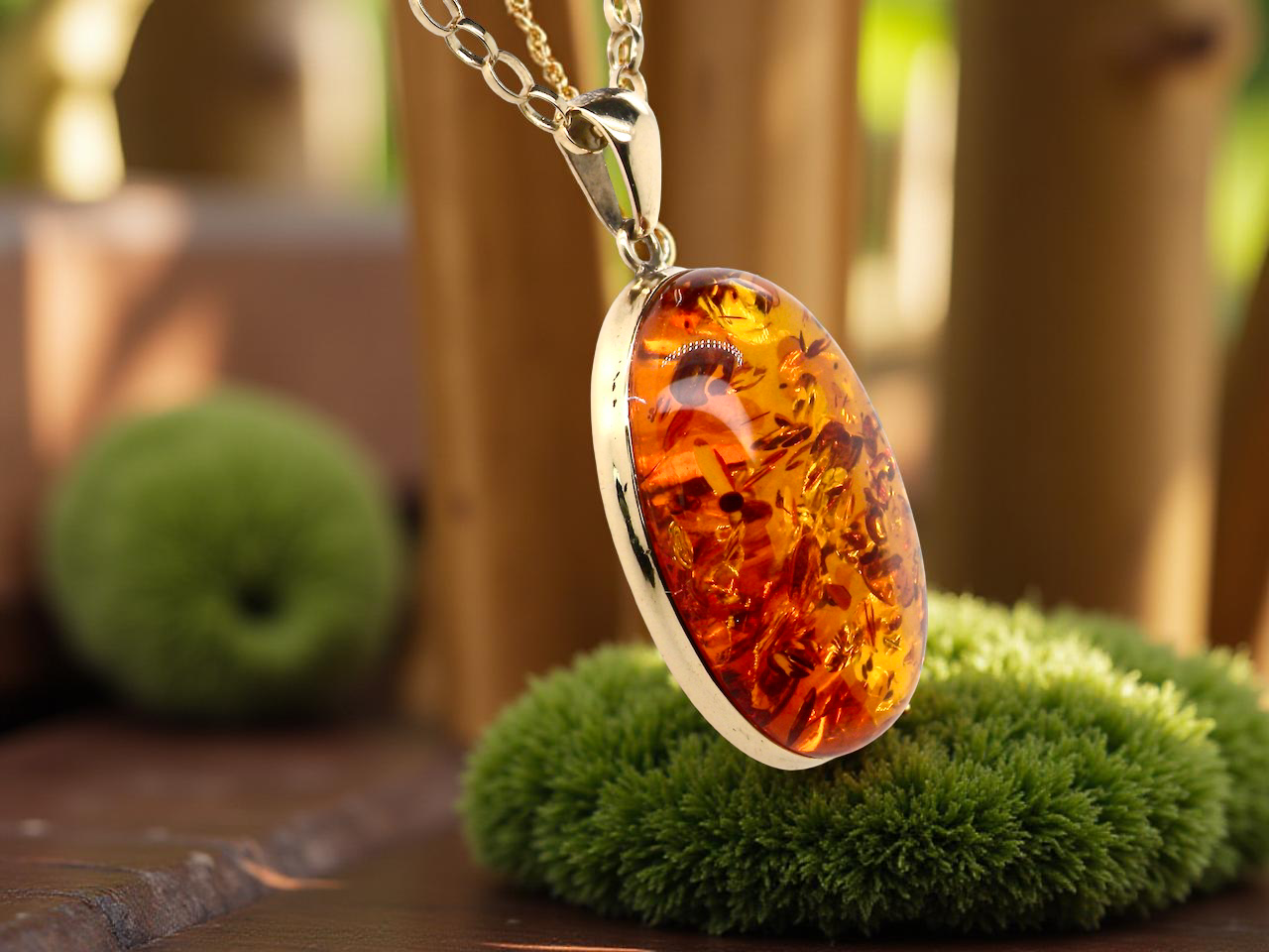 Amber pendant necklace on a stand with a blurred natural background