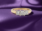 Gold ring with three diamonds on a purple fabric background