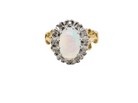 An 18 carat gold cluster ring. Features an oval opal centre stone with excellent play of colour with a predominance of watery purple and flashes of orange, and luminous green.
Measures 11x7mm.