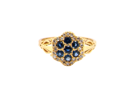 An 18 carat gold cluster ring.&nbsp; The centre a floral combination of seven sapphires, each 2.5mm, mid to dark blue.