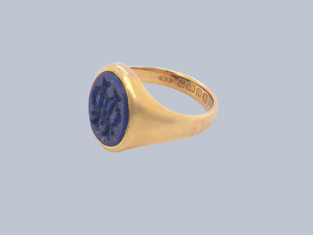 An 18 carat gold signet ring set with an oval lapis lazuli stone. This measures 12x9.5mm and has a carved intaglio seal engraved onto the stone. 