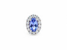 An oval halo ring featuring a central blue tanzite gemstone surrounded by a double halo of small clear round diamonds in a silver-colored setting, isolated on a white background.