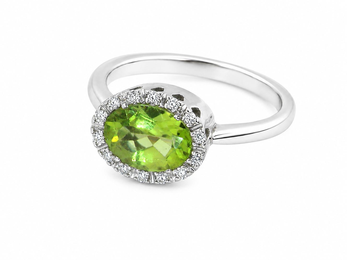 An 18 carat white gold* cluster ring. Features and oval shaped peridot gemstone, 
