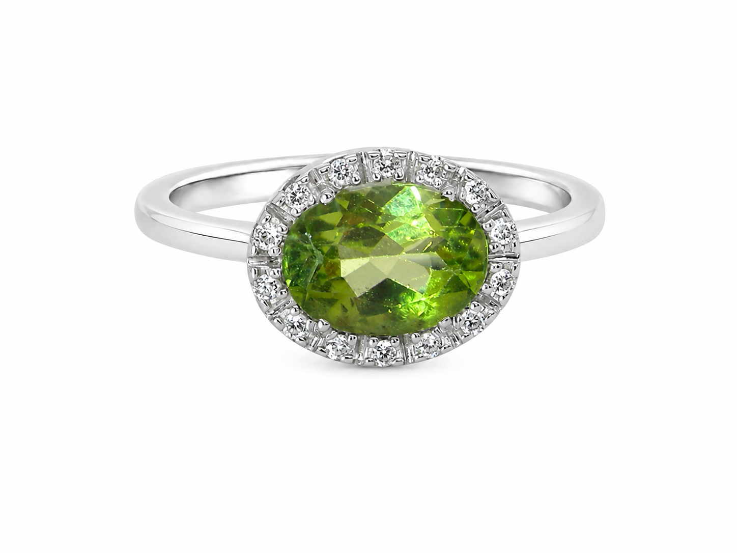 An 18 carat white gold* cluster ring. Features and oval shaped peridot gemstone, measures 8.5x6.5mm.
