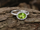 An 18 carat white gold* cluster ring. Features and oval shaped peridot  measures 8.5x6.5mm.
