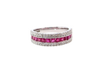 An 18 carat white gold half hoop ring. A triple row design with a line of channel set calibre cut rubies running along the centre , 
