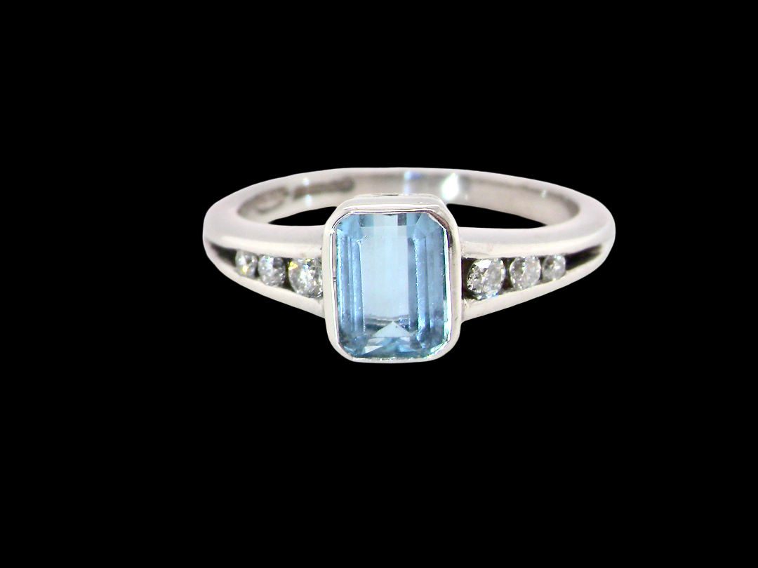 An 18 carat white gold ring, features a rectangular step cut aquamarine, measures 7x5mm (st one carat) , fine clarity. Rim setting.
