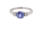 An 18 carat white gold three stone ring. Centre stone a round tanzanite
Each side a brilliant cut white diamond
